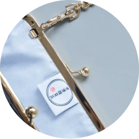 Close-up of the interior lining, logo tag, and gold kiss-lock frame on the Mt. Fuji Pocket Bag at Grandmama Store in Hong Kong.