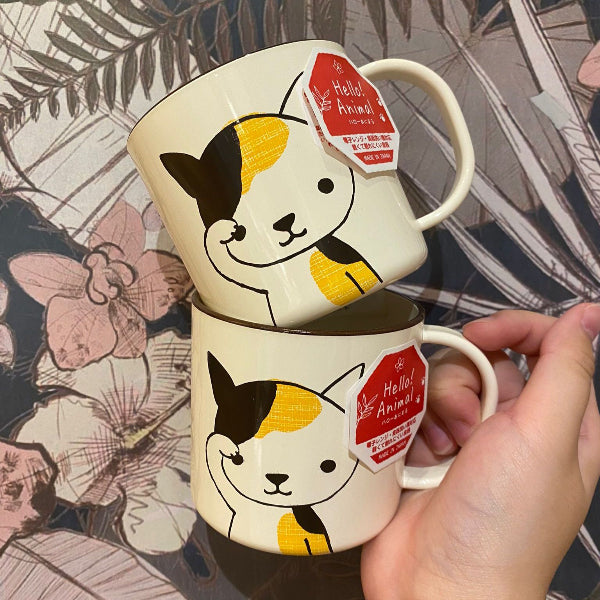 Cream-colored Cat Cup with calico cat illustration held in hand at Grandmama Store in Hong Kong