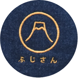 Extreme close-up of gold Mount Fuji logo embroidery on dark denim fabric at Grandmama Store in Hong Kong.
