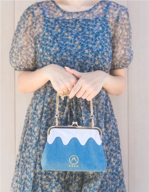 Front view of a model holding the Light Blue denim Mt. Fuji Pocket Bag with gold chain strap at Grandmama Store in Hong Kong.