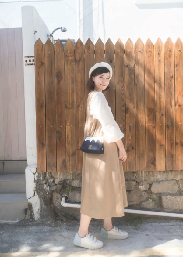Full shot of a model wearing the Dark Blue denim Mt. Fuji Pocket Bag with gold chain strap at Grandmama Store in Hong Kong.
