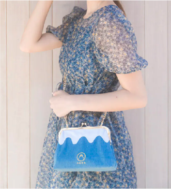 Model holding the Light Blue denim Mt. Fuji Pocket Bag with gold chain strap at Grandmama Store in Hong Kong.