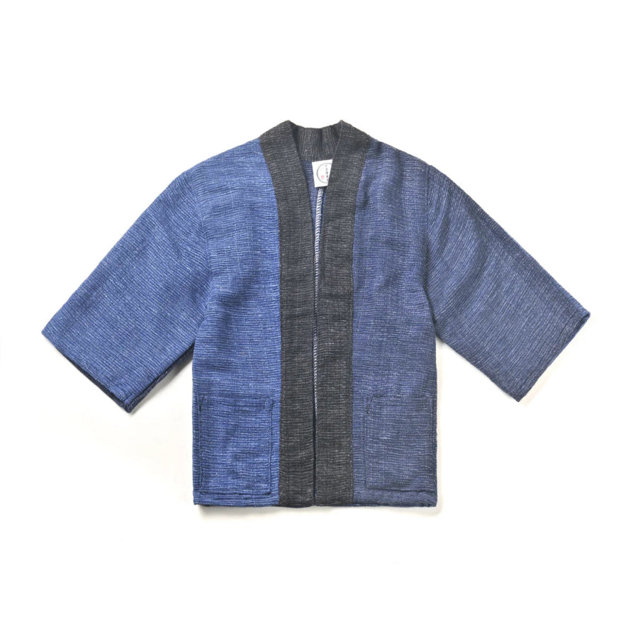 A flat lay image of a hand-cranked Kimono jacket in Moonlight color featuring textured medium blue and charcoal gray handwoven cotton fabrics at Grandmama Store in Hong Kong.