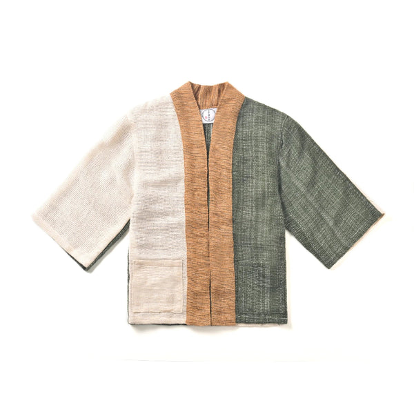 A flat lay image of a panel-design hand-cranked Kimono jacket in Yakushima color featuring textured cream, forest green, and tan handwoven cotton fabrics at Grandmama Store in Hong Kong.