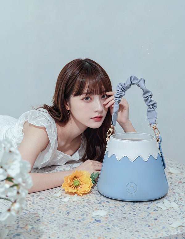 Model posing with the light blue and white Mt. Fuji Goen Bag in Snow with a ruffled leather strap at Grandmama Store in Hong Kong.